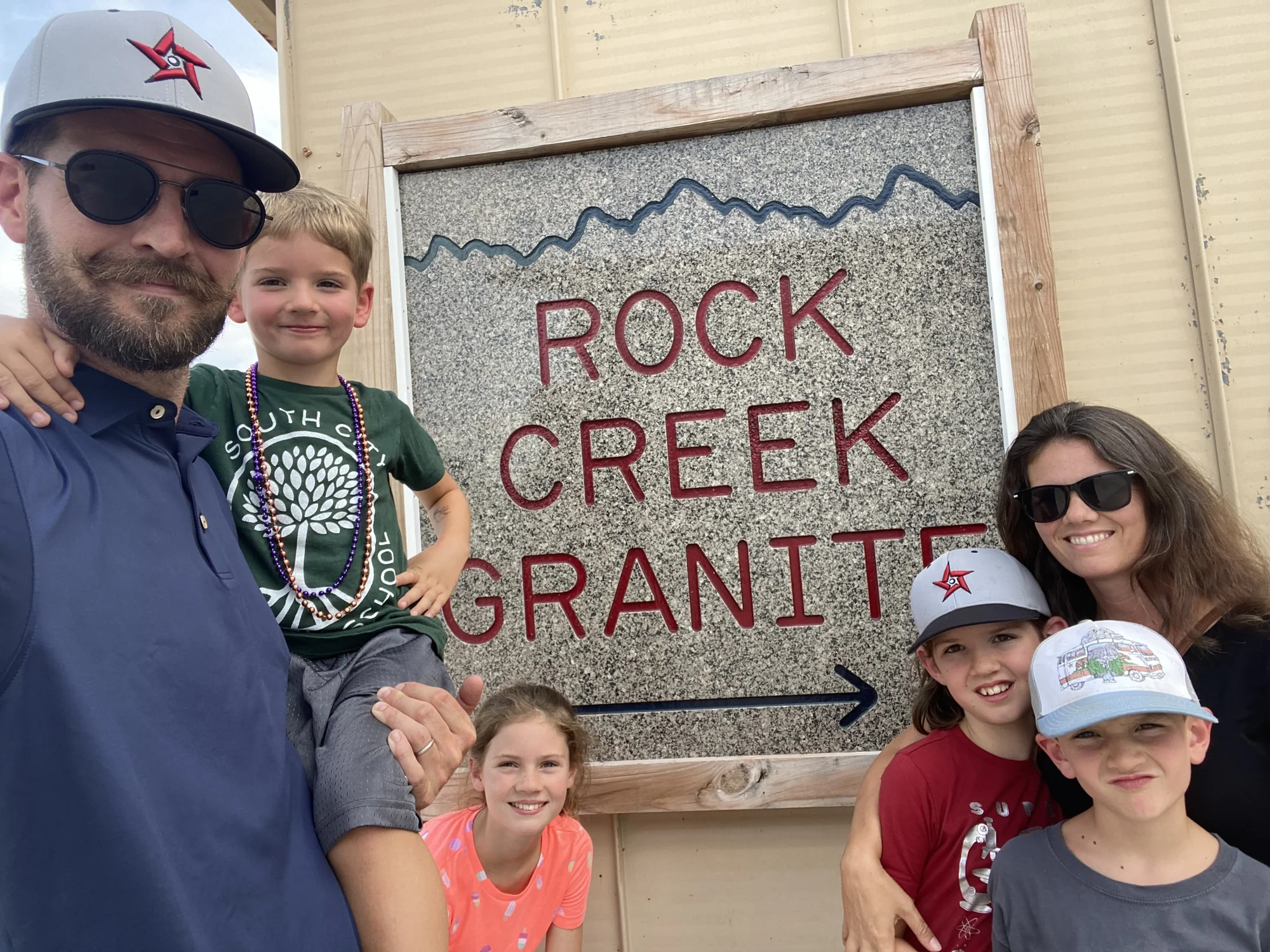 Ryan, Audrey and their four kids in front of the Rock Creek Granite sign