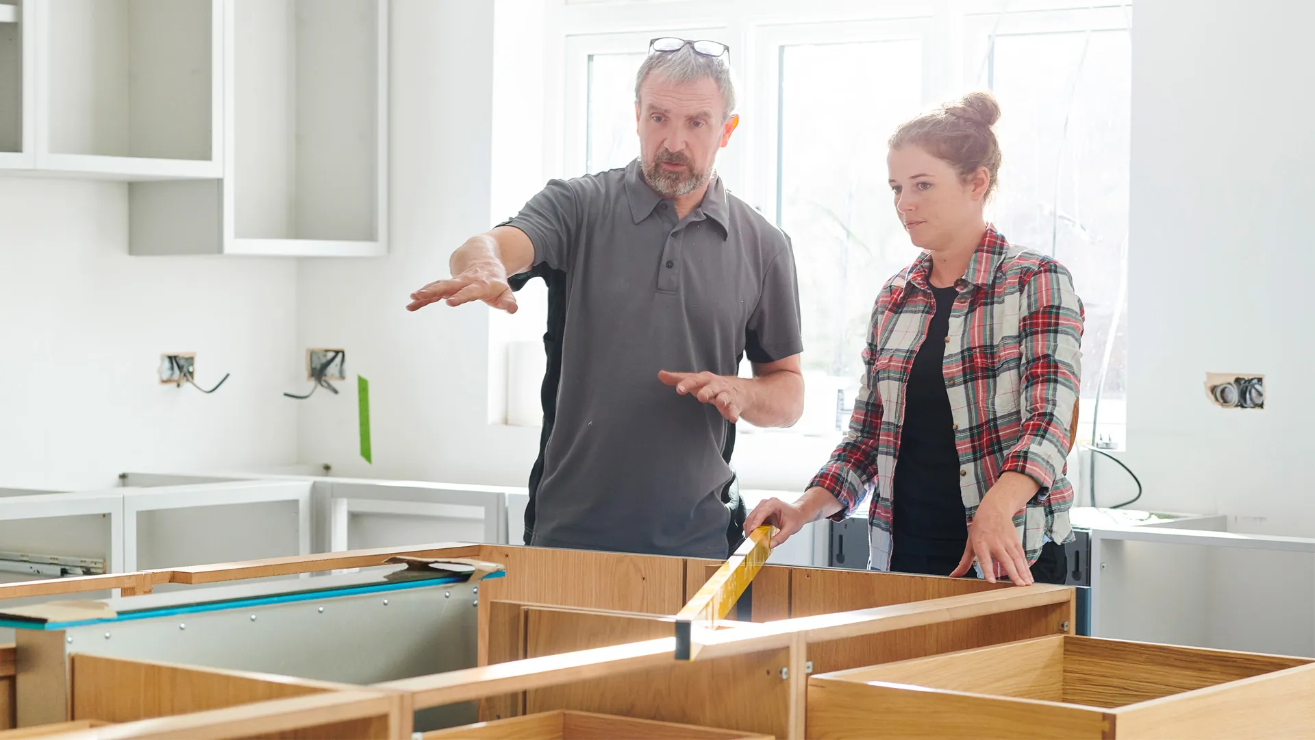 Two tradespeople checking a cabinet run with a level before templating